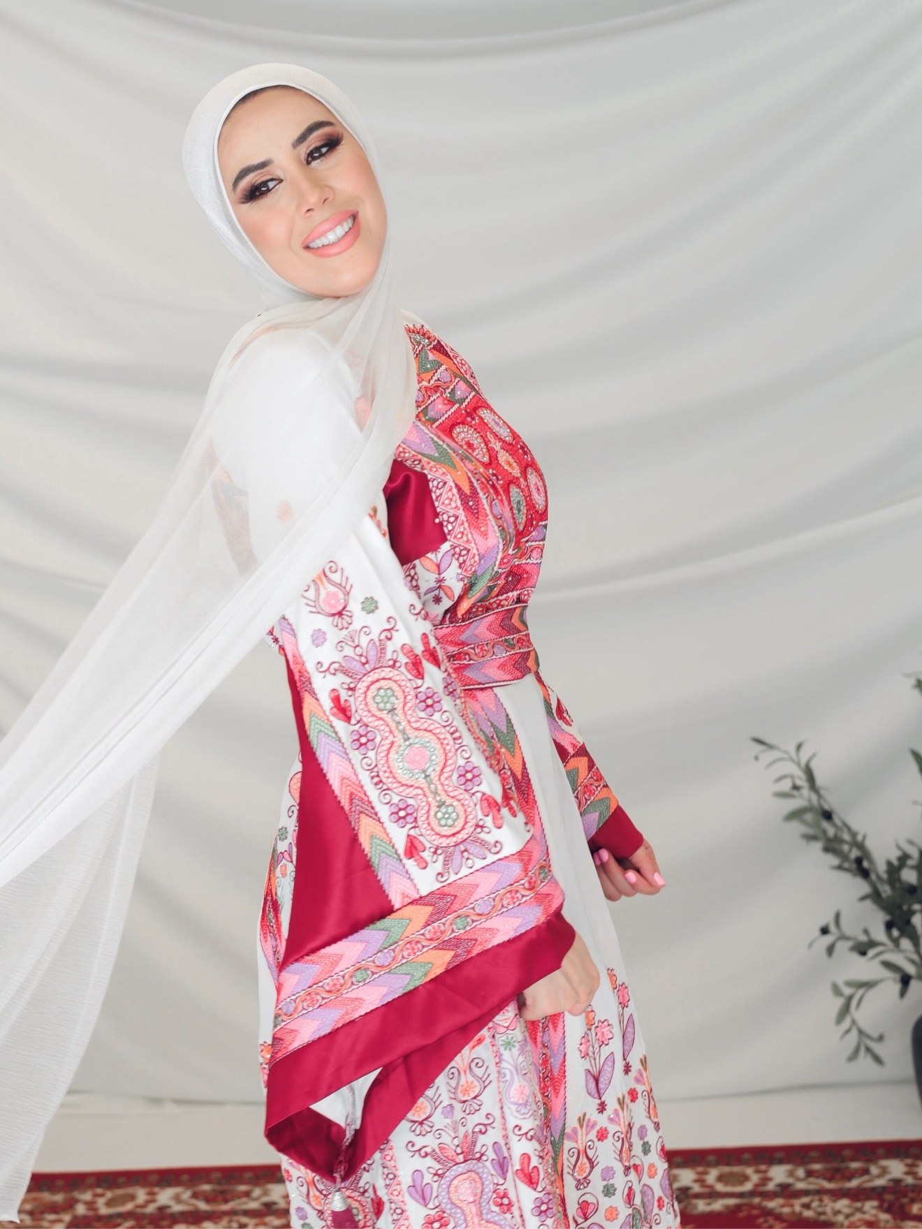 Woman in a white hijab wearing a Palestinian embroidered thobe, photographed by Kamar photography