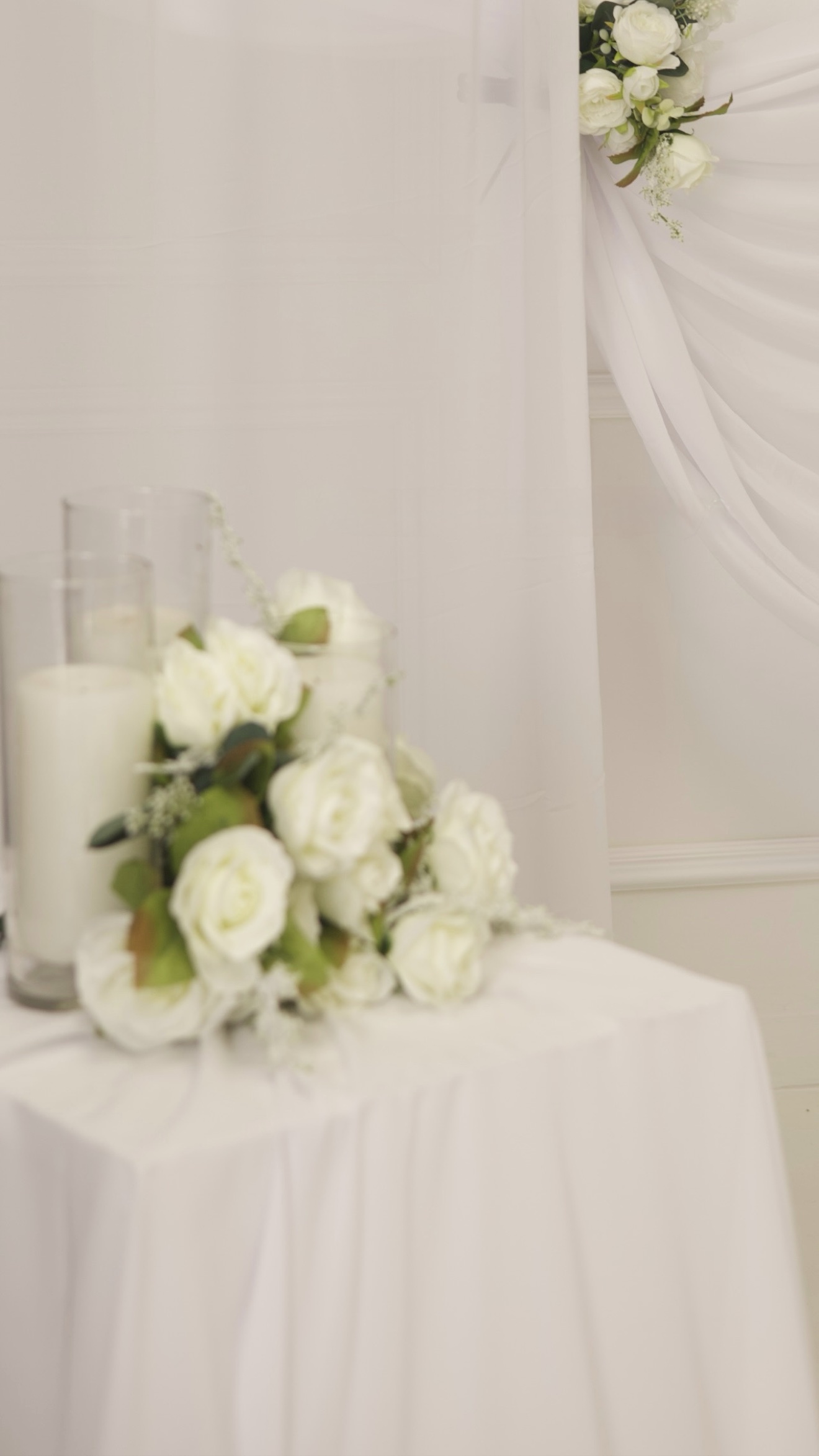 White roses and candles on a draped table, nikkah decor detail photographed by Kamar photography