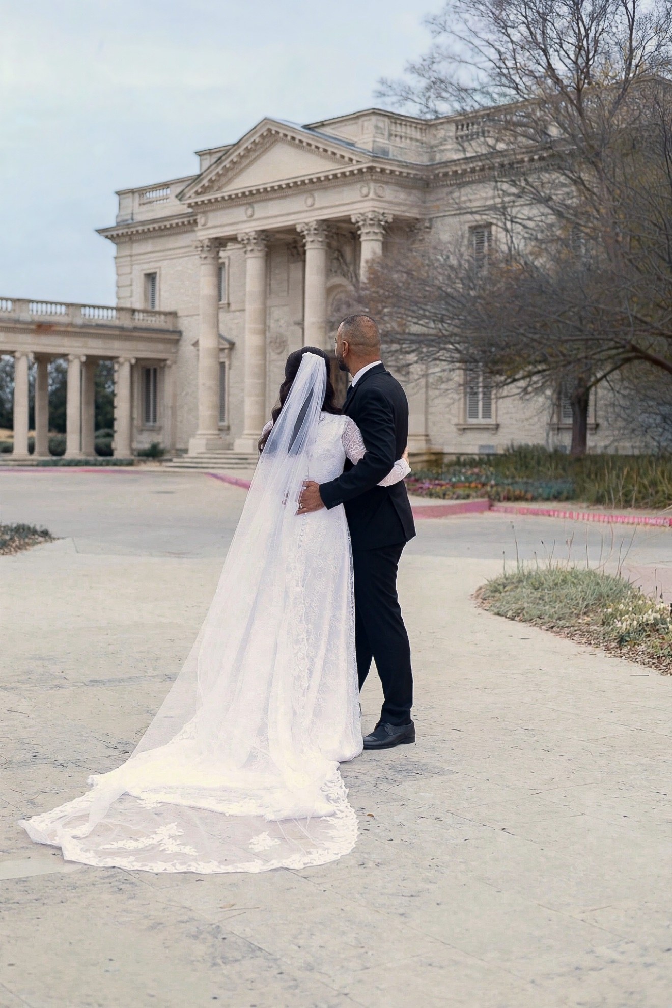 Bride and groom standing together outdoors, photographed from behind by Kamar photography