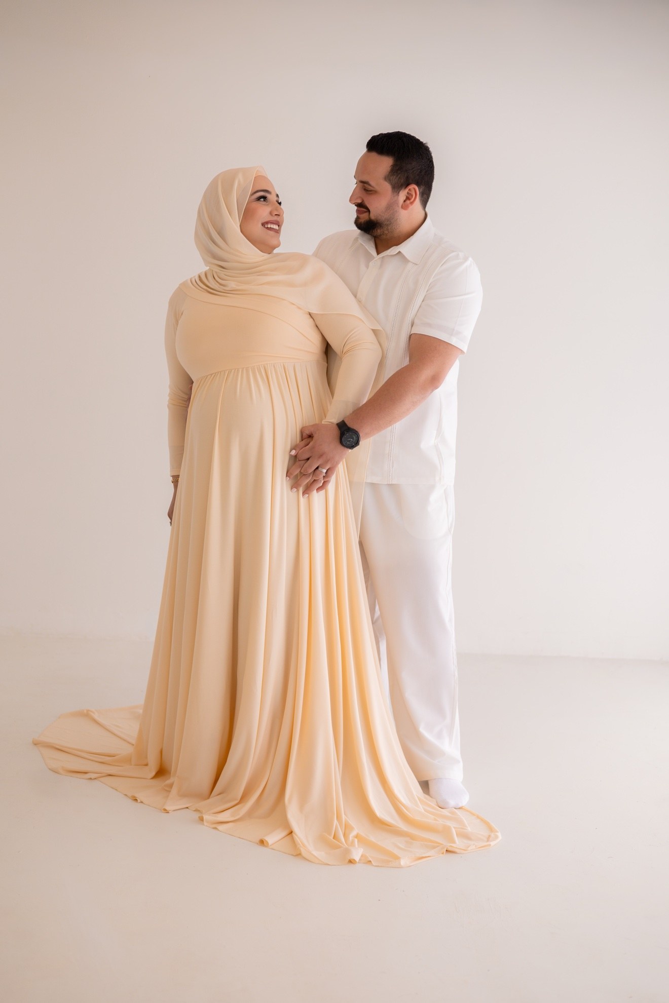 Pregnant woman in a peach gown with her partner, photographed by Kamar photography