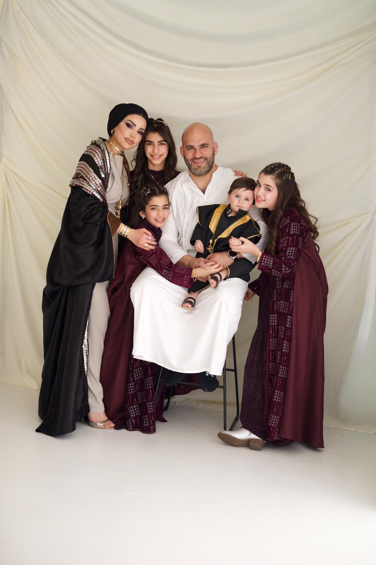 Family group portrait gathered against white drapes, photographed by Kamar photography