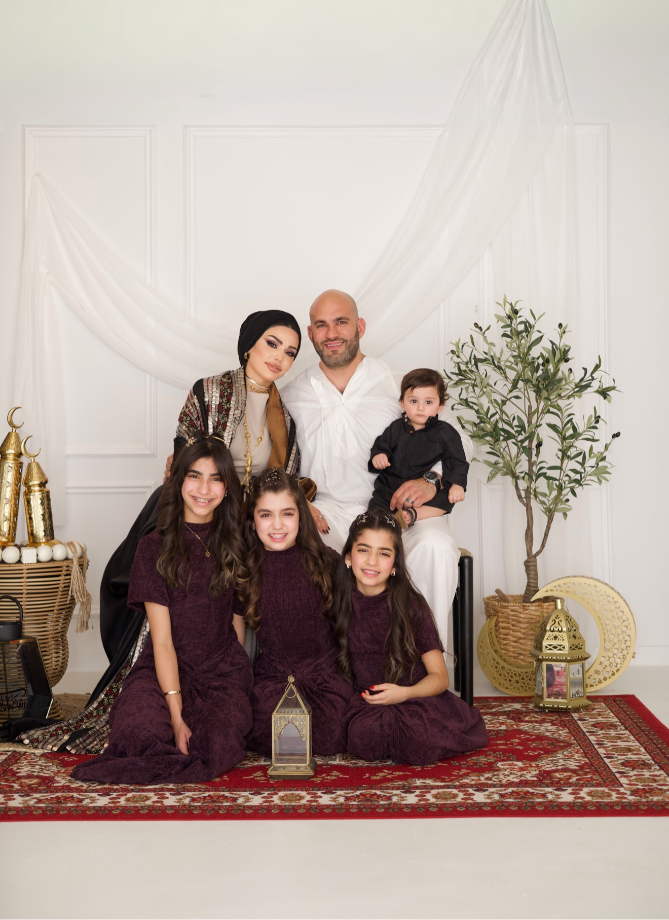 Family seated together in a Ramadan setting with gold lanterns, photographed by Kamar photography