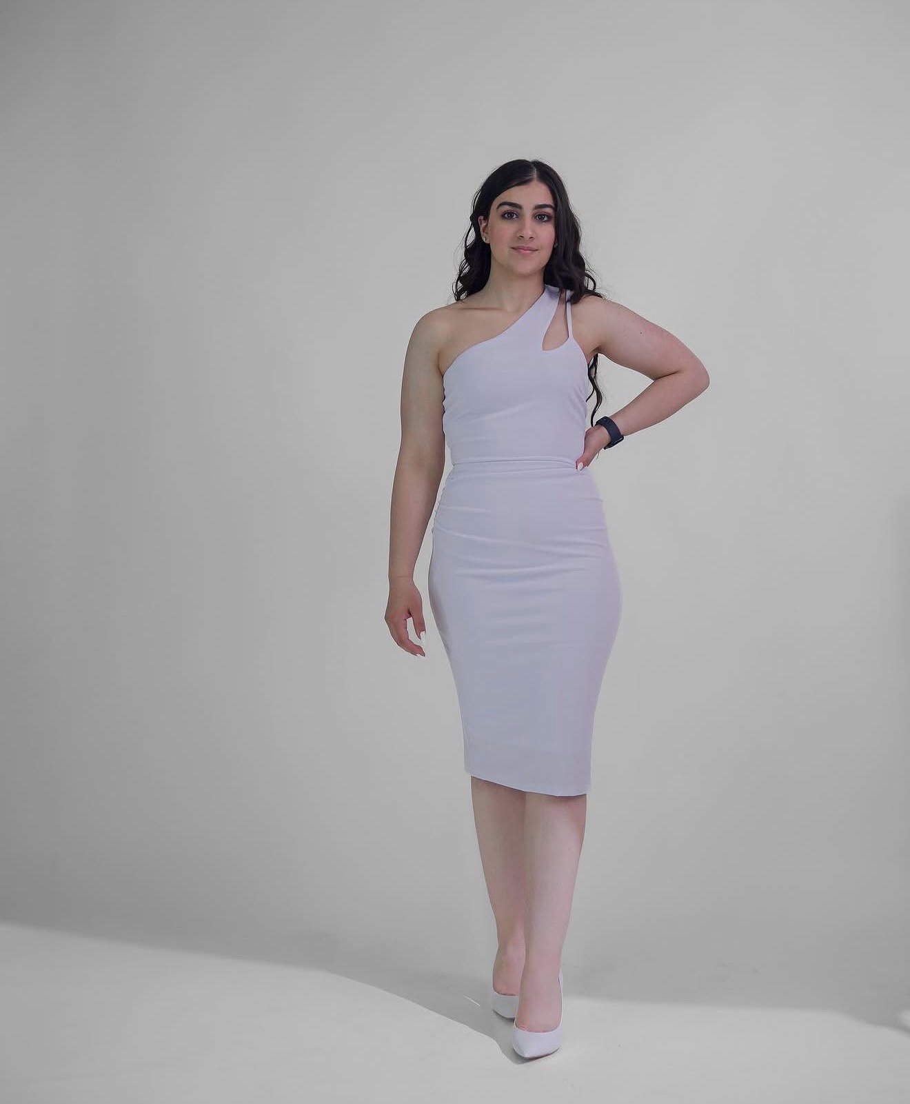Young woman in a white one-shoulder dress, studio portrait photographed by Kamar photography