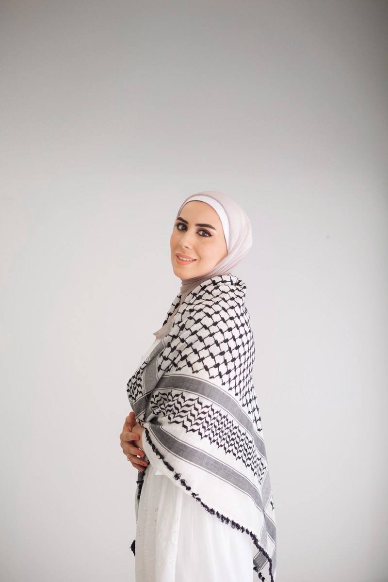 Woman in a white hijab and black-and-white keffiyeh, photographed by Kamar photography
