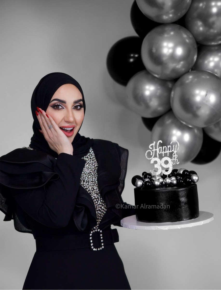 Woman in a black hijab posing with a Happy 39th birthday cake, photographed by Kamar photography