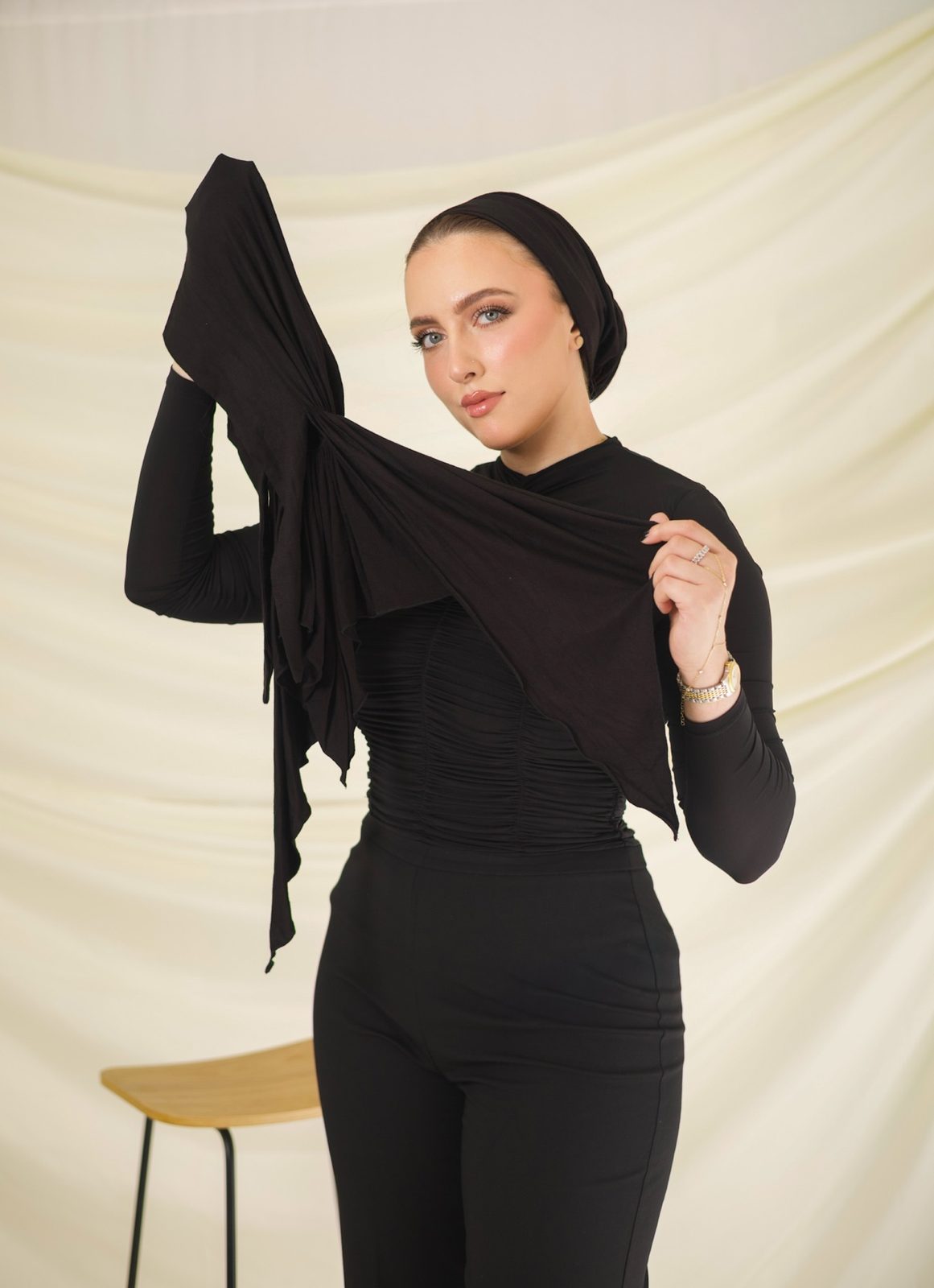 Woman in black presenting fabric against a cream backdrop, photographed by Kamar photography