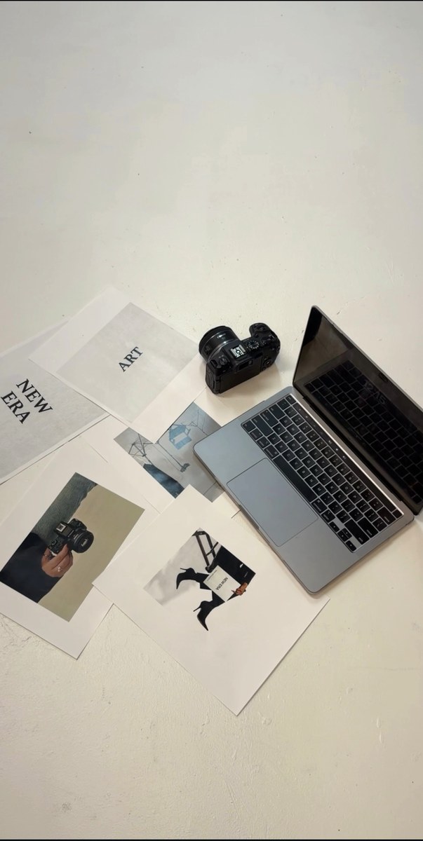 Camera, laptop, and creative prints arranged on a studio floor, photographed by Kamar photography