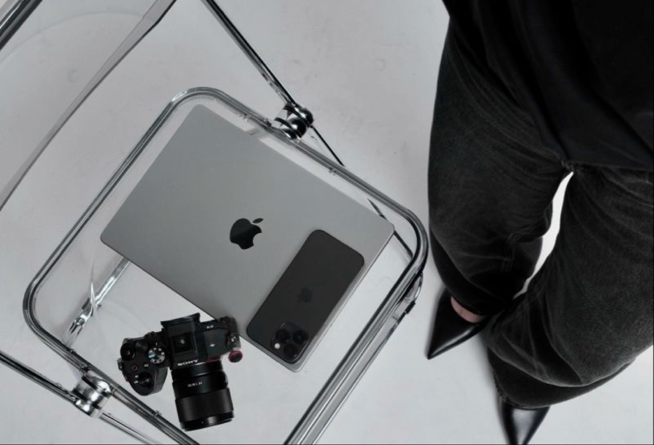 Laptop, phone, and camera arranged on a glass chair, seen from above